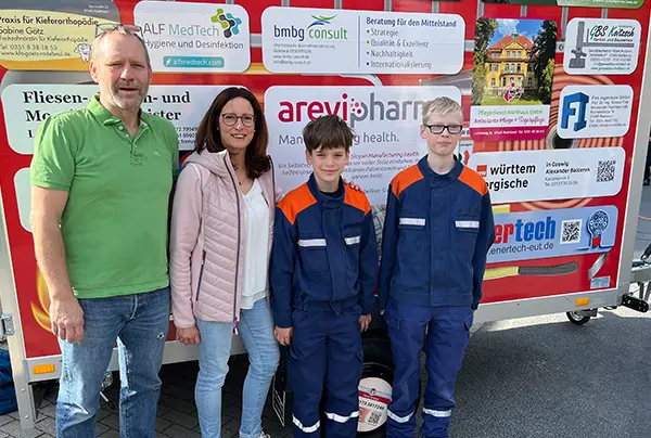 Barbara Flach und Jan-Michael Albrecht vor Brandschutzmobil mit zwei Kindern der Freiwilligen Feuerwehr